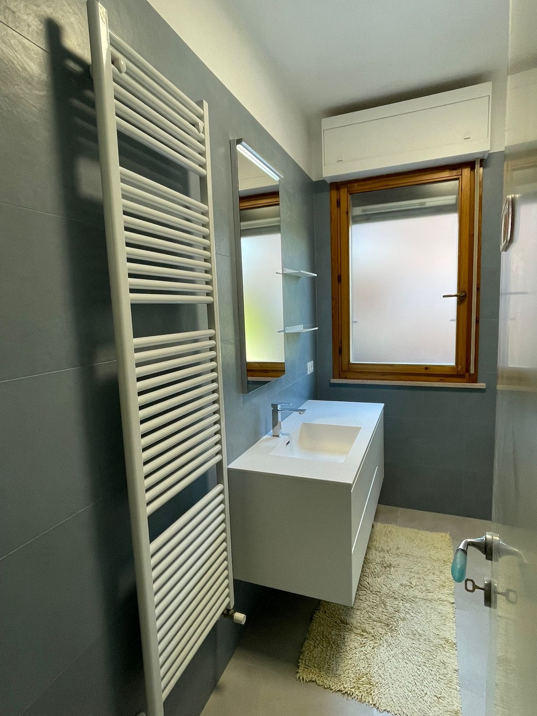 Rifacimento bagno stile celeste con lavabo sospeso bianco e scaldasalviette — Senigallia 2025