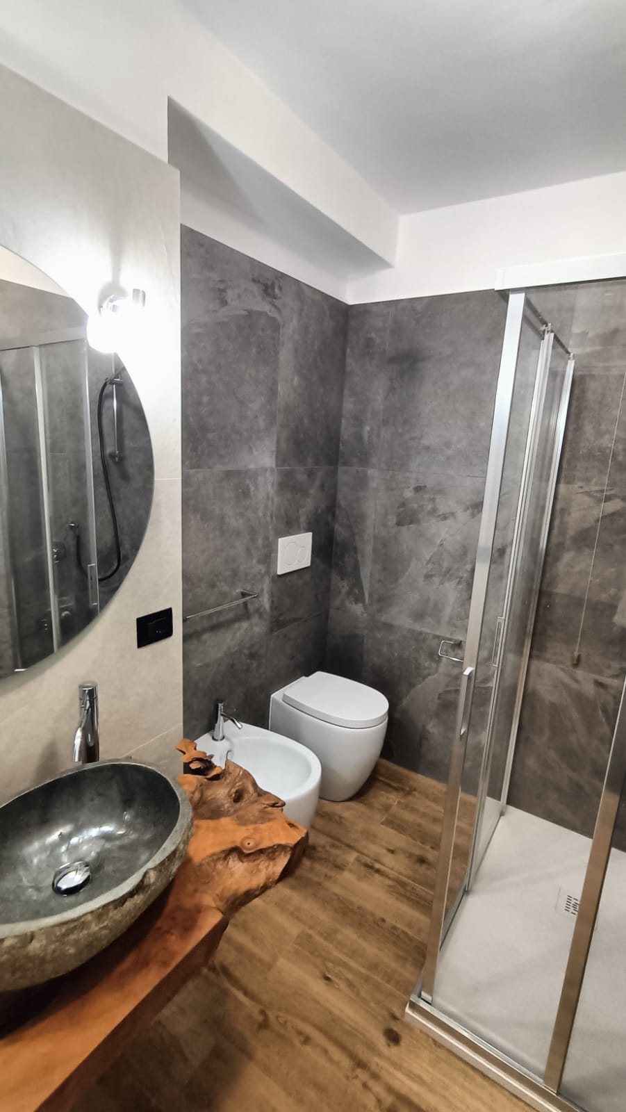 Bagno ristrutturato ad Arcevia: sanitari a terra, box doccia vetro trasparente, gres effetto pietra antracite — Fratelli Venturi