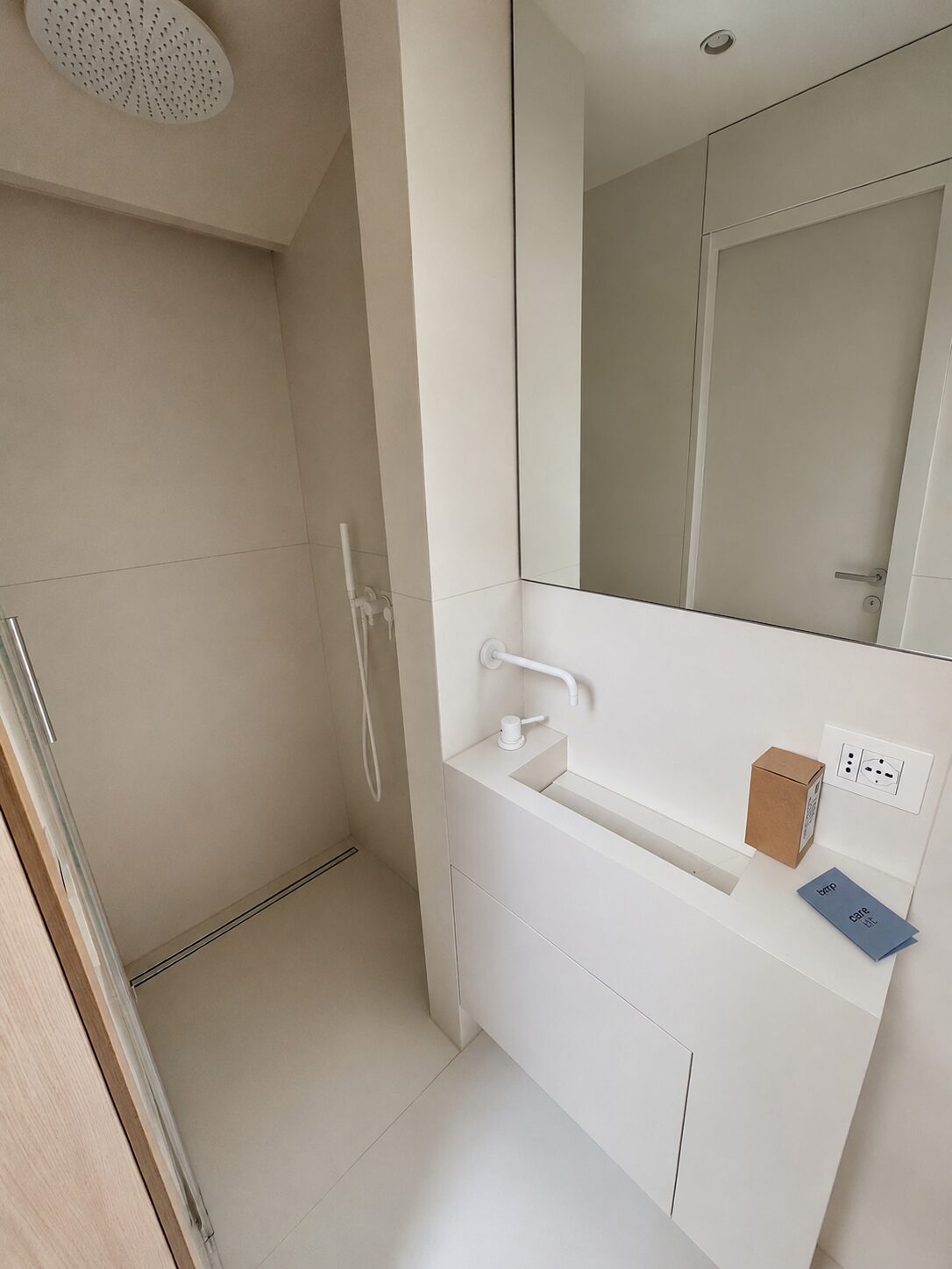 Bagno di servizio total white con grandi lastre, soffione tondo a soffitto e lavabo integrato &mdash; Senigallia centro 2026