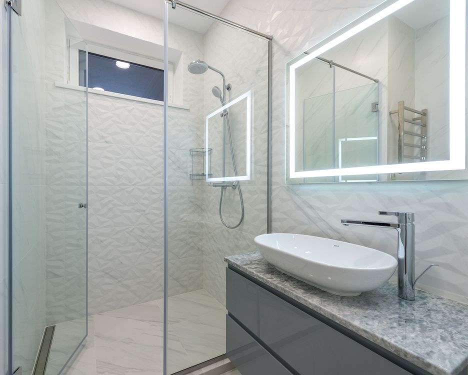 Bagno con specchio LED e cabina doccia in vetro